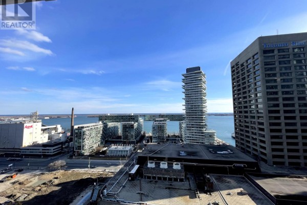 City skyline view from a high floor with clear blue skies and water visible. - 1610 - 28 Freeland Street, Toronto