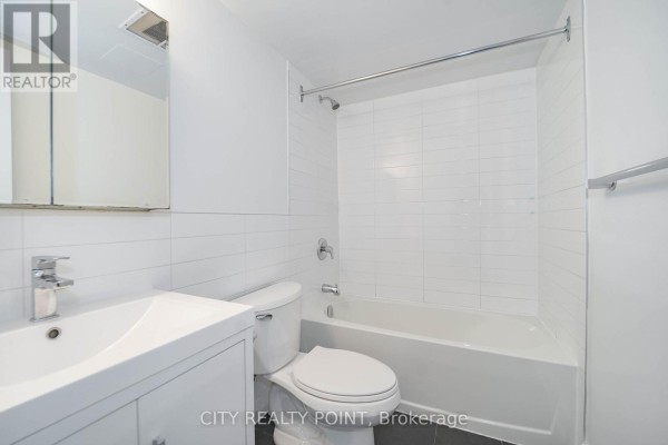 Bathroom with a white vanity, toilet, and bathtub with white tiled walls. - 1610 - 33 Isabella Street, Toronto
