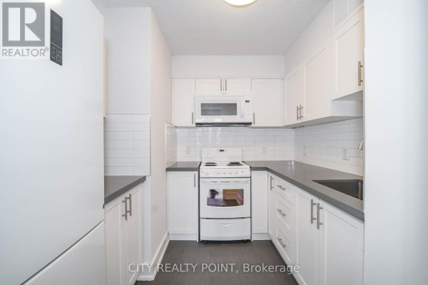 White galley kitchen with grey countertops, white cabinets, oven, and refrigerator. - 1610 - 33 Isabella Street, Toronto