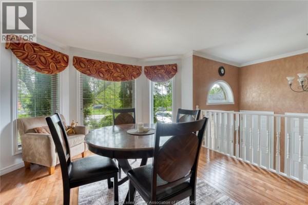 Dining area with round wooden table, chairs, and adjacent living room. - 1610 Chornoby Crescent, Tecumseh