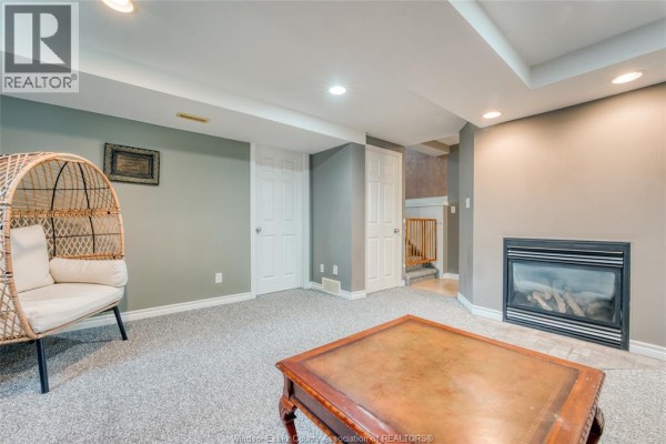 Basement living room with fireplace and wicker chair - 1610 Chornoby Crescent Tecumseh