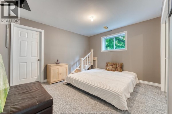 Bedroom with bed, dresser, and stairs - 1610 Chornoby Crescent Tecumseh