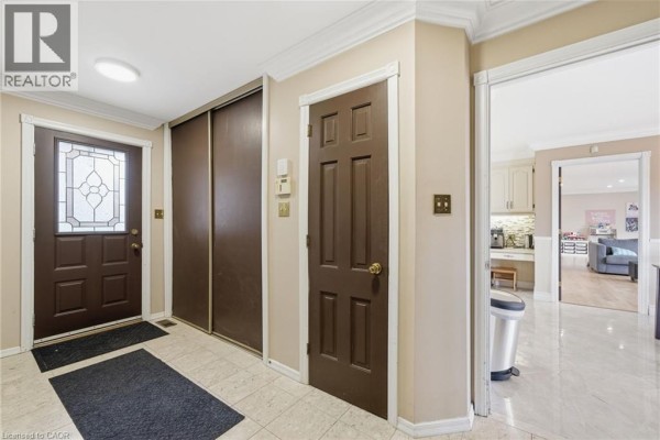 Interior hallway with beige walls, brown doors, a mirrored closet, and a glass-paneled front door. - 1610 Concession 7 Road, Hampton