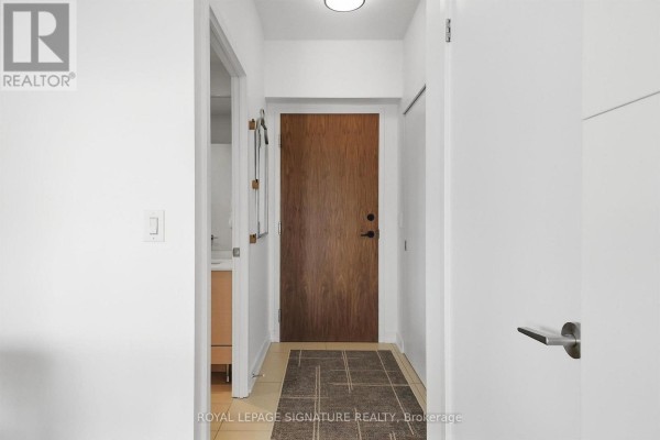 Apartment entrance hallway with wood door, tiled floor, and minimalist decor. - 1611 - 1 Market Street, Toronto