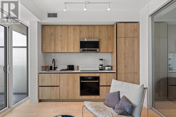 Modern building hallway with textured walls, carpeted floor, and bright vertical LED strip lighting. - 1611 - 127 Broadway Avenue, Toronto