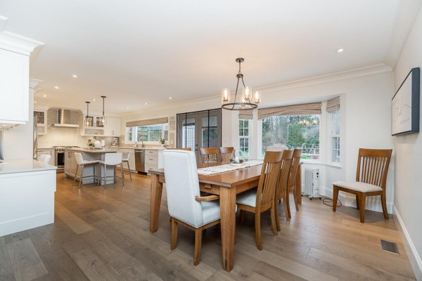 Open concept dining room and kitchen with a large wooden dining table and island with bar stools. - 16114 20 Avenue, Surrey