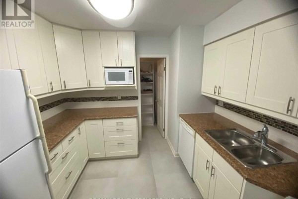 U-shaped kitchen with white cabinets, granite countertops, mosaic tile backsplash, and stainless steel sink. - 1612 - 3605 Kariya Drive, Mississauga