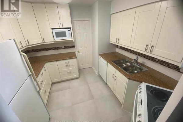 Kitchen with white cabinetry, granite counters, mosaic tile backsplash, sink, dishwasher, and refrigerator. - 1612 - 3605 Kariya Drive, Mississauga