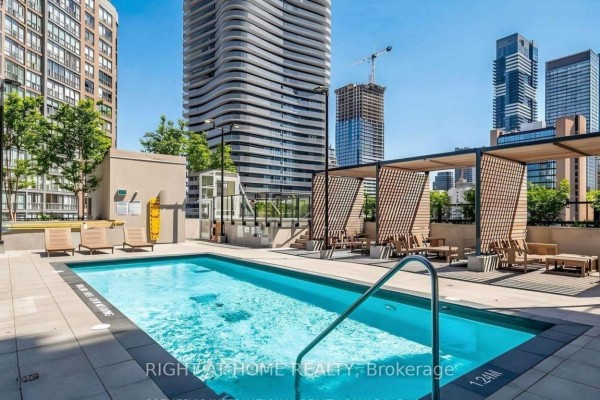 Outdoor swimming pool area with lounge chairs and modern seating under pergolas. - 1612 - 955 Bay Street, Toronto