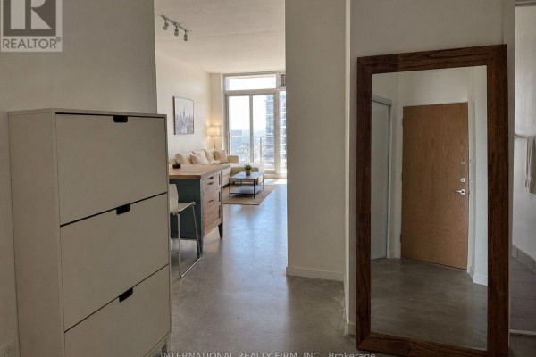 Hallway view showing a white shoe cabinet, dining area, and entrance to the living room. - 1613 - 150 Sudbury Street S, Toronto