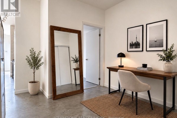 A small workspace with a desk, chair, artwork, and a tall mirror in the hallway. - 1613 - 150 Sudbury Street S, Toronto