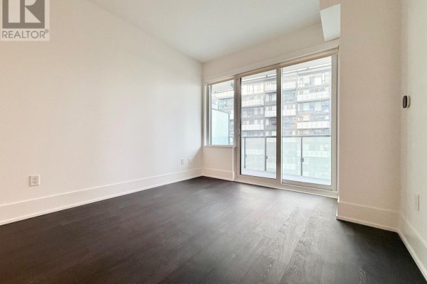 Bedroom with dark wood floors, white walls, and sliding glass doors to balcony. - 1613 - 480 Front Street W, Toronto