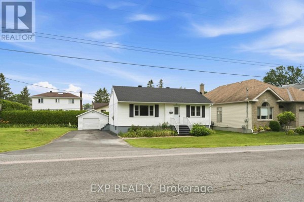 Street view of a white bungalow with a black roof and a detached garage. - 1613 Queensdale Avenue, Ottawa