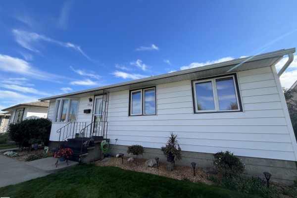Side exterior view of a white stucco bungalow with new windows and aluminum gutters. - 16131 110b Av Nw, Edmonton