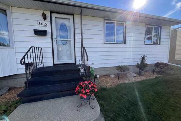 Close-up of the front door with stairs, mailbox, and decorative plants. - 16131 110b Av Nw, Edmonton