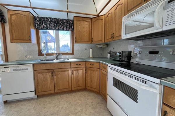 Kitchen with light oak cabinets, white appliances, and a light blue countertop. - 16131 110b Av Nw, Edmonton