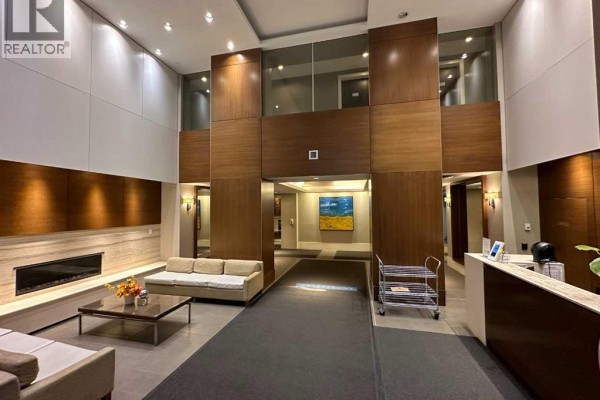 A hotel-style lobby with wood paneling, a modern fireplace, and seating areas. - 1615, 222 Riverfront Avenue Sw, Calgary