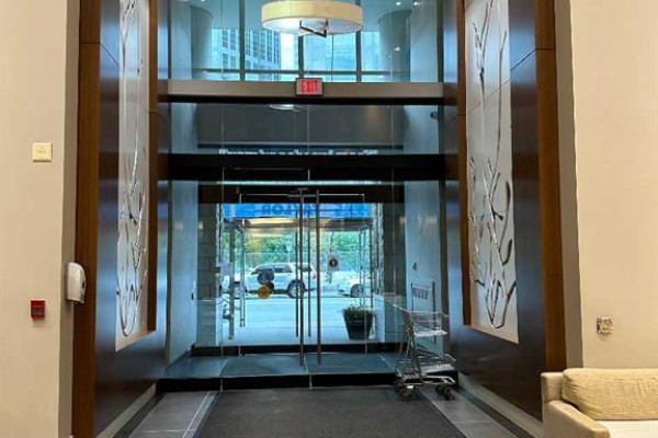 Glass double doors leading into a building lobby with a reception desk and seating. - 1615, 222 Riverfront Avenue Sw, Calgary