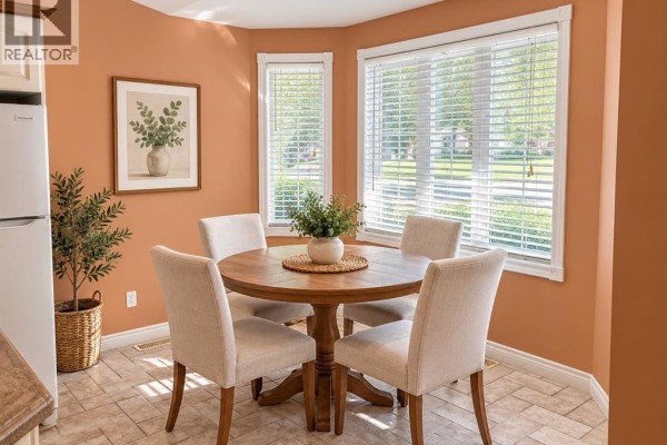 Round wooden dining table with four upholstered chairs in a windowed corner. - 1615 Blue Heron, Windsor