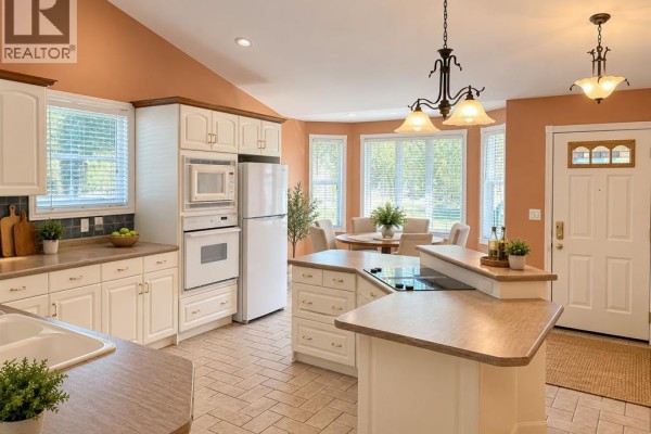 Bright kitchen with white cabinets, a bay window, and a front door. - 1615 Blue Heron, Windsor
