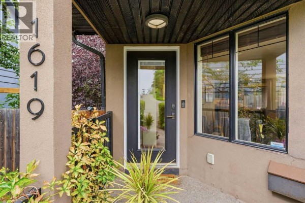 Close-up of the front door of a townhouse, featuring a glass insert, black frame, and house numbers '619'. - 1619 24 Avenue Sw, Calgary