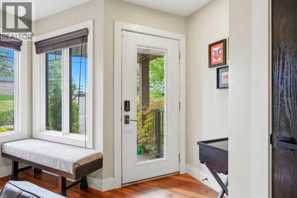 Interior view of a foyer with a bench seat by a large window and a white door leading outside. - 1619 24 Avenue Sw, Calgary