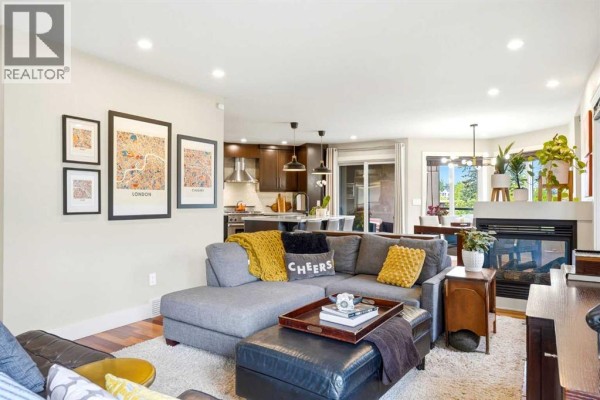 Living room with a grey sectional sofa, fireplace, and view of the open-concept kitchen and dining area. - 1619 24 Avenue Sw, Calgary