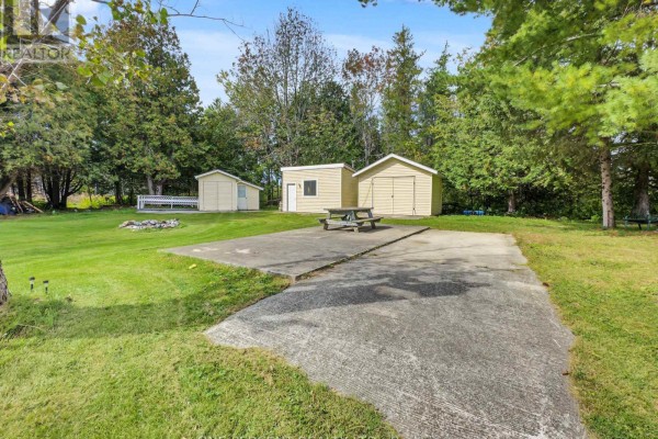 Concrete pad with a picnic table and fire pit in a grassy backyard. - 1619 Centreville Road, Stone Mills