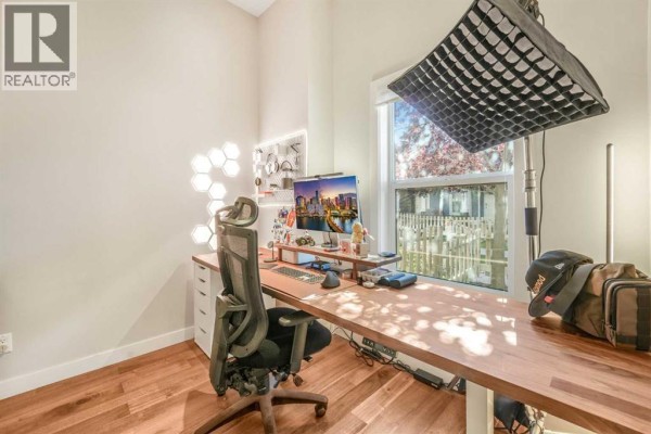 Office space with a standing desk, ergonomic chair, computer, and a large window overlooking the yard. - 162, 2802 Kings Heights Gate Se, Airdrie