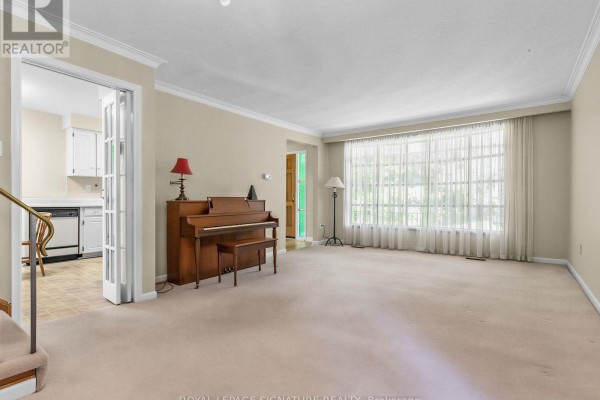 Living room with beige carpet, a grand piano, a large window, and French doors to the kitchen. - 162 Bathgate Drive, Toronto