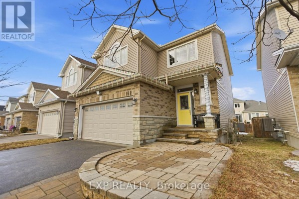 Close-up exterior view of the entrance to a beige townhouse with a yellow front door and stone accents. - 162 Bert Hall Street, Arnprior