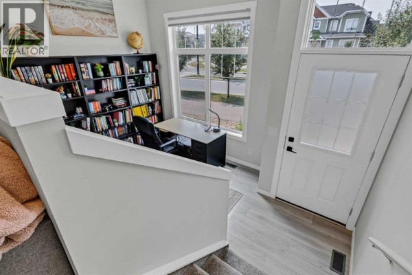 Entryway with a desk, chair, and floor-to-ceiling bookshelf next to a large window. - 162 Chinook Gate Boulevard Sw, Airdrie