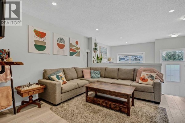 Living room featuring a large sectional sofa, wooden coffee table, and plush rug. - 162 Chinook Gate Boulevard Sw, Airdrie