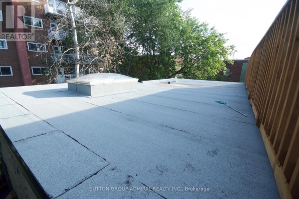 Flat rooftop with a large skylight and a wooden fence bordering the edge. - 162 Daly Avenue, Ottawa