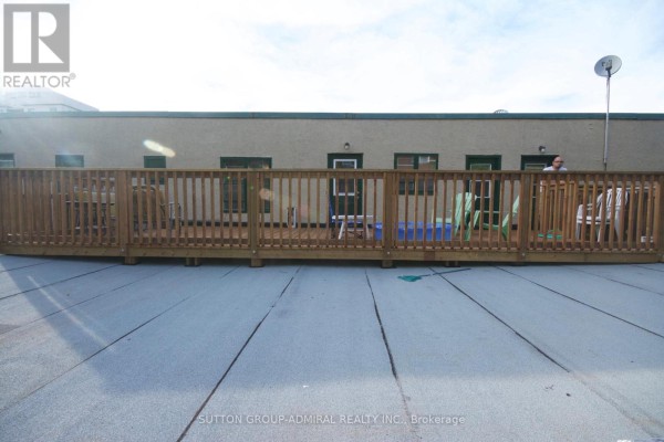 Rooftop deck with wooden railing, chairs, and tables overlooking a city skyline. - 162 Daly Avenue, Ottawa