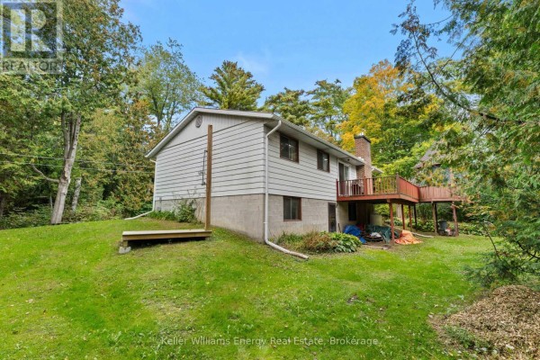 Rear view of the white house showing a concrete foundation and a wooden deck. - 162 Jones Road, Cramahe