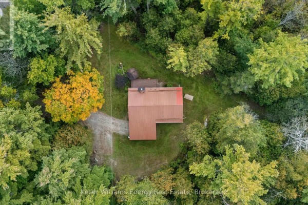 Aerial view looking down at the house with a metal roof amidst a dense forest. - 162 Jones Road, Cramahe