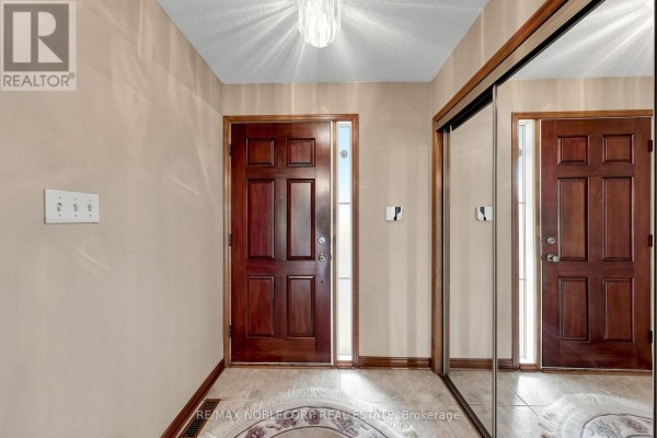 Interior entryway with a dark wood front door, adjacent single door, and a large mirrored closet. - 162 Venetian Crescent, Vaughan