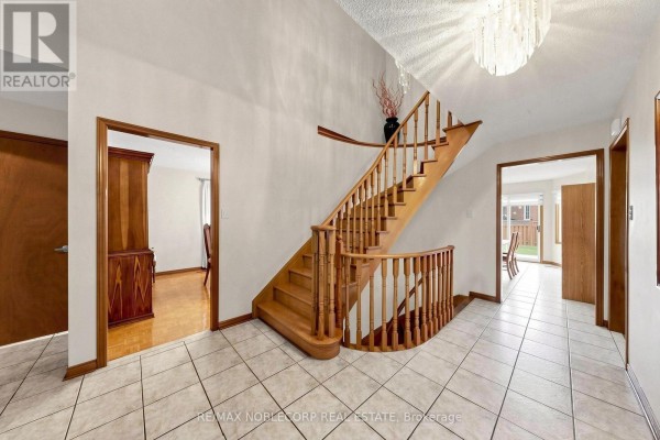 Foyer with a wooden staircase, light-colored tile floor, and doorways to other rooms. - 162 Venetian Crescent, Vaughan