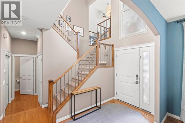 Foyer with a grand staircase, wood flooring, an entryway table, and doors to other rooms. - 1621 Strathcona Drive Sw, Calgary