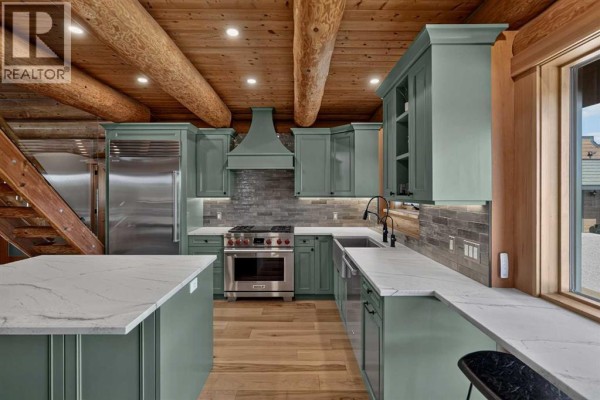 View of a modern kitchen with green cabinets, stainless steel appliances, and a large island. - 162104 376 Street W, Rural Foothills County