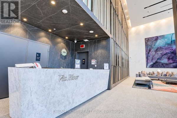 Lobby with a marble reception desk labeled "Via Bloor", dark marble walls, and elevator. - 1622 - 585 Bloor Street E, Toronto