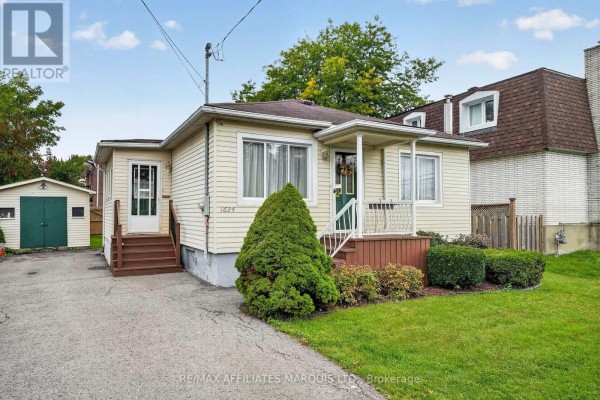 Side view of a light yellow vinyl-sided bungalow with a detached garage and a paved driveway. - 1624 Aubin Avenue, Cornwall