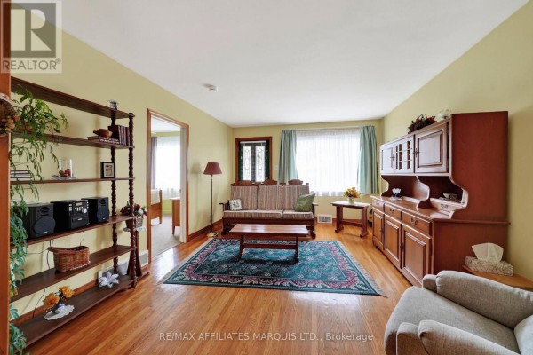 Living room with light yellow walls, a sofa, a wooden hutch, a wooden bookshelf, and a view into a hallway. - 1624 Aubin Avenue, Cornwall