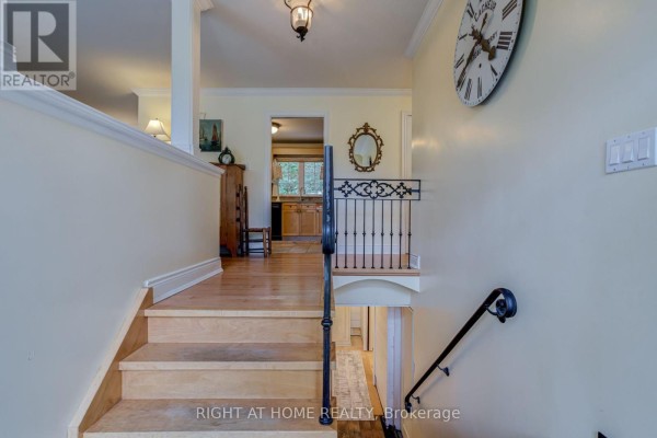Interior staircase with wood steps and a decorative metal railing leading downstairs. - 1627 Rometown Drive, Mississauga