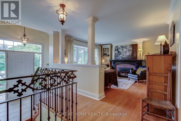 View from the landing of a home with a staircase, pillars, and living room in background. - 1627 Rometown Drive, Mississauga