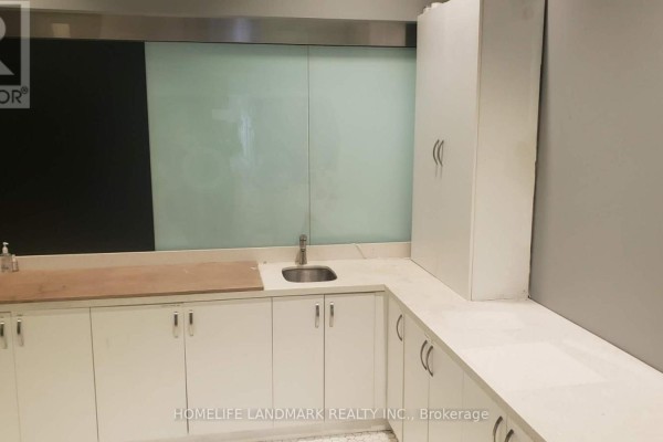 Small kitchenette area with white cabinets, a sink, and frosted glass panels. - 163 - 4750 Yonge Street, Toronto