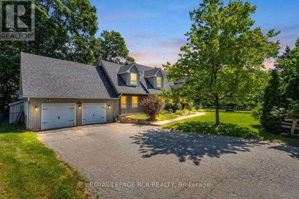Front exterior view of a house with a grey roof, light wood siding, and a double garage at dusk. - 163 Confederation Street, Halton Hills
