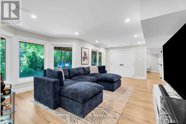 Navy sectional sofa and hardwood floors in living room with large windows overlooking backyard swings - 163 Confederation Street Halton Hills