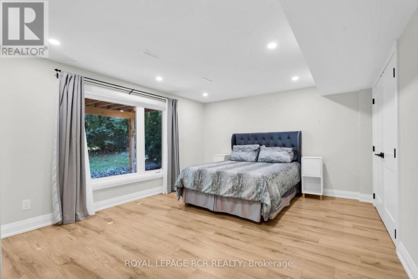 Bedroom with queen bed, large window, and wood floors - 163 Confederation Street Halton Hills
